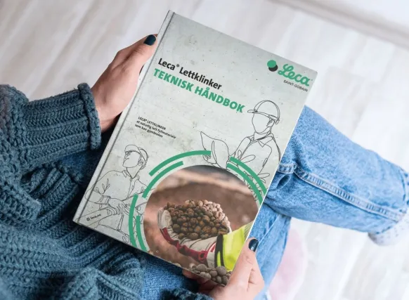 Hender holder Leca® Lettklinker sin tekniske håndbok. Forsiden viser tittelen «Teknisk håndbok» og illustrasjon av Leca Lettklinker i bruk.