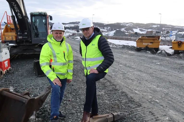 Jon Hauge og Frank Nornberg fra Leca i gule refleksjakker og hjelmer på en grusvei foran anleggsmaskiner ved Leistadkrysset.