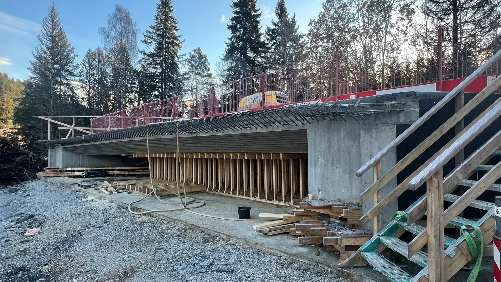 Ny betongbru under bygging ved Kobbervoll på E134. Undersiden av brudekket med forskaling og støtteverk er synlig, med armering langs kanten og midlertidig rekkverk på toppen. Skog og blå himmel i bakgrunnen.