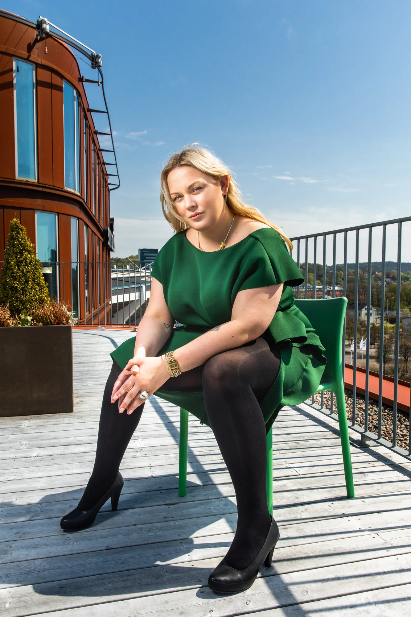 Amanda Borneke sitter på en grønn stol på en takterrasse, iført en grønn kjole, med blikket vendt mot kameraet.
