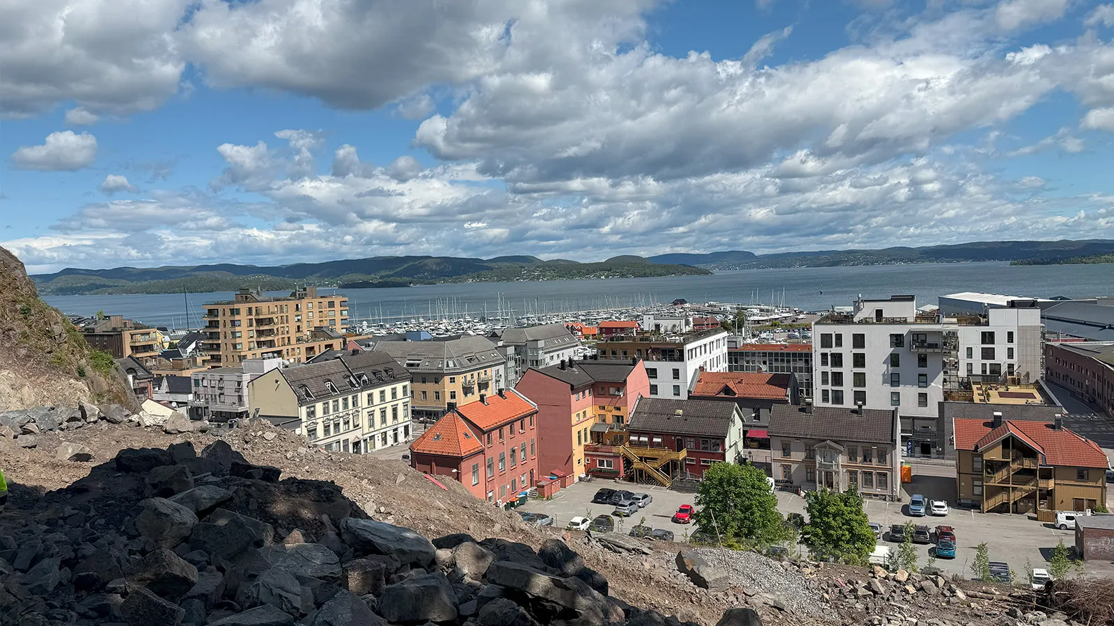 tsikt fra anleggsområdet i fjellsiden ned mot Holmestrand sentrum og Oslofjorden, med boligblokker og småhus i forgrunnen.