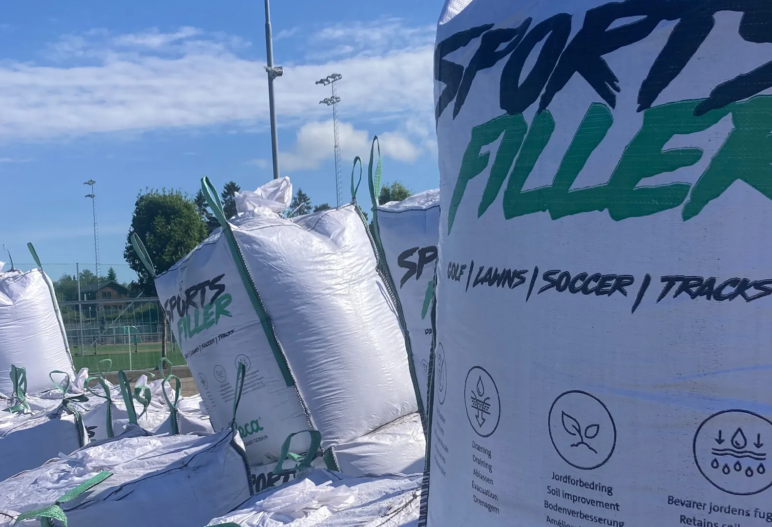 Storsekker med Leca Sportsfiller plassert ved en kunstgressbane.