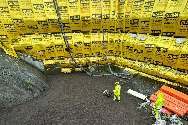 Oversiktsbilde av grøft kledd med gule isolasjonsmatter, der Leca® Lettklinker fylles og komprimeres.